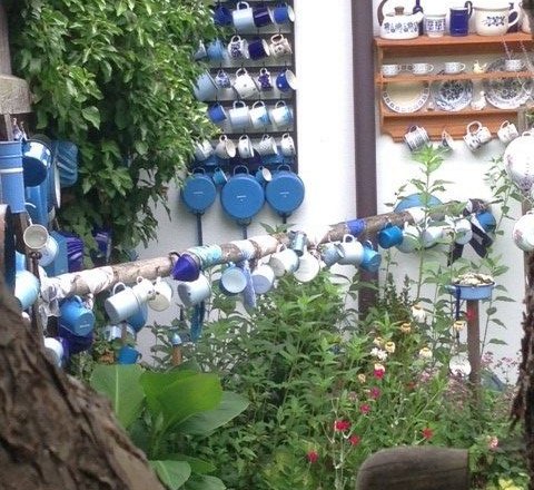 Nostalgic eye-catchers, © Erika Pascher A garden with lots of colorful cups hanging on walls and poles.