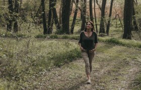 Space for awareness & trust in nature, © Ines Steiner Woman walking along a forest path, surrounded by trees and greenery.
