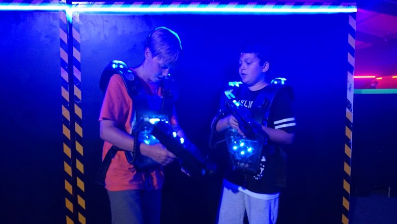 Laser tag for two, © Suracon OG Two boys in a laser tag arena with glowing vests and laser guns.