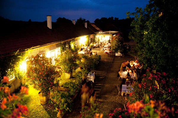 Oberstockstall Estate, © Robert Herbst Evening garden terrace with illuminated tables and plants.