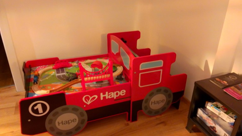 Adventure vacation for railroad enthusiasts, © Bernhard Kaar Red toy bed in the shape of a locomotive with toy train.