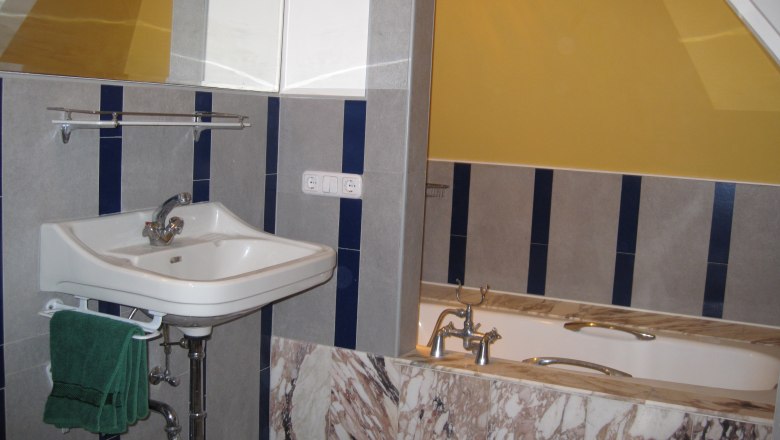 Bathroom, © Stein Bathroom with washbasin, bathtub and yellow wall.