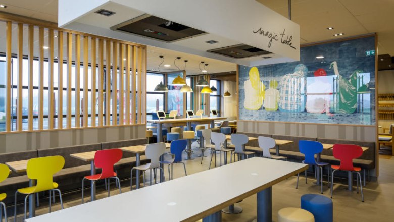 McDonalds, © McDonalds Interior view of a modern McDonald's restaurant with colorful chairs and tables.