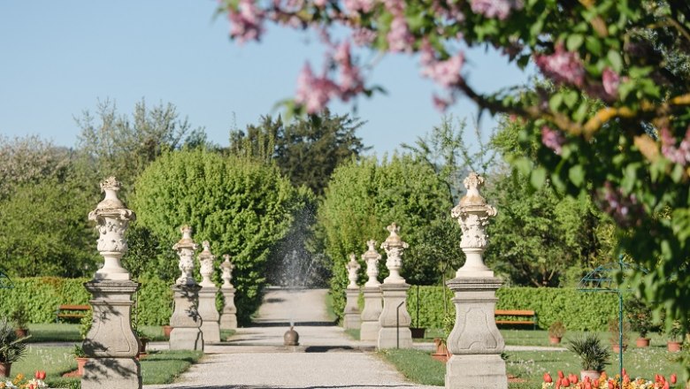 Historic courtyard garden, © Doris Schwarz König A well-kept garden path with statues and blossoming trees in spring.
