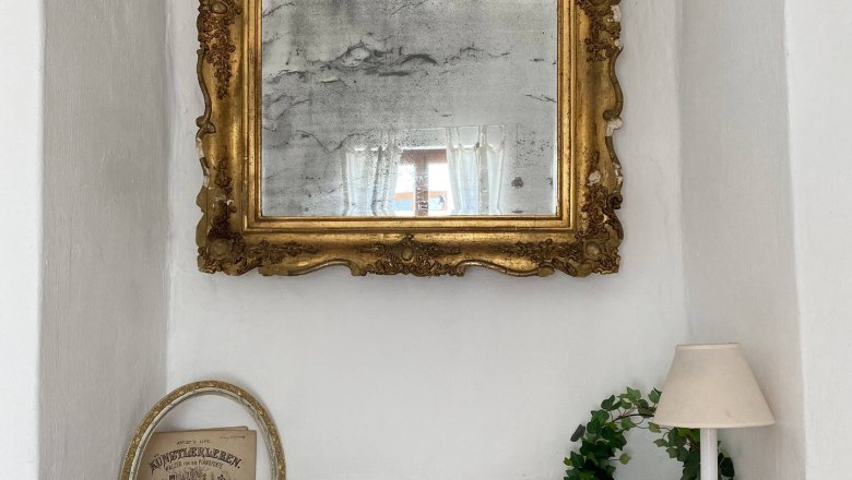 Window decoration, © Familie Stagard An antique mirror with golden decoration above a windowsill with decoration.
