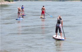 Stand up paddling, © www.standuppaddeln.at Four people stand up paddling on a river.