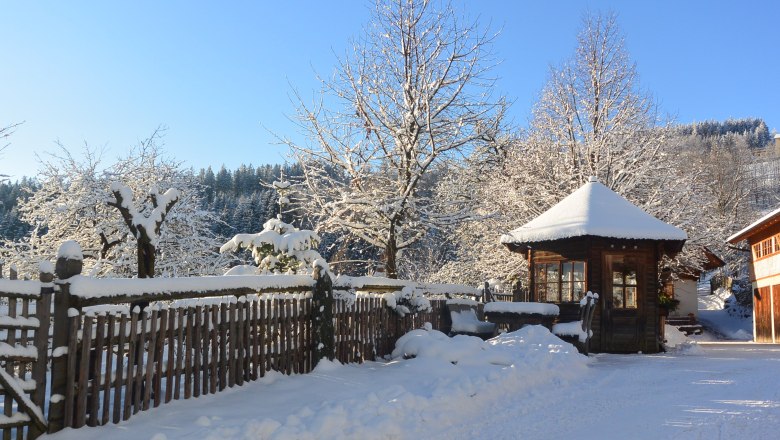 Winter mood, © Erika Kronaus Snow-covered landscape with wooden hut, wooden fence and trees under a blue sky.