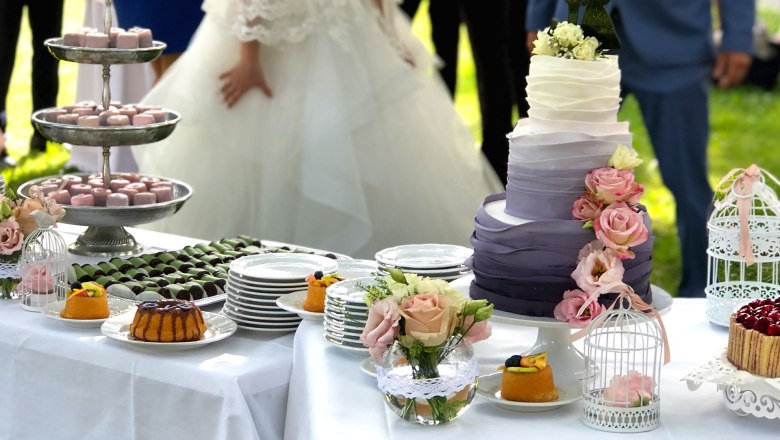 Sweet temptation from the castle confectionery, © Günter Brentrup Wedding cake and desserts on an outdoor table with the bride and groom.