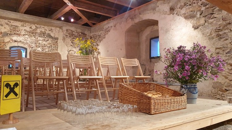 Concerts on the upper floor, © Marktgemeinde Hochneukirchen-Gschaidt Interior view of a rustic room with wooden chairs, flowers and a table with glasses and pastries.
