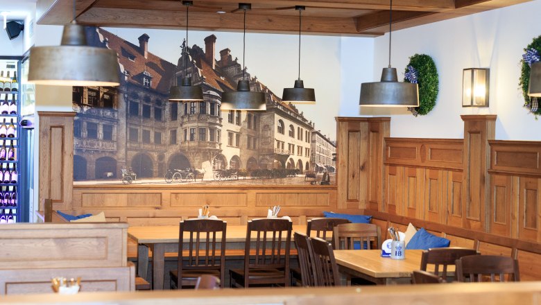 Hofbräu, © Ewald Rauscher Interior view of a traditional Bavarian restaurant with wooden furniture and mural of the Hofbräuhaus.