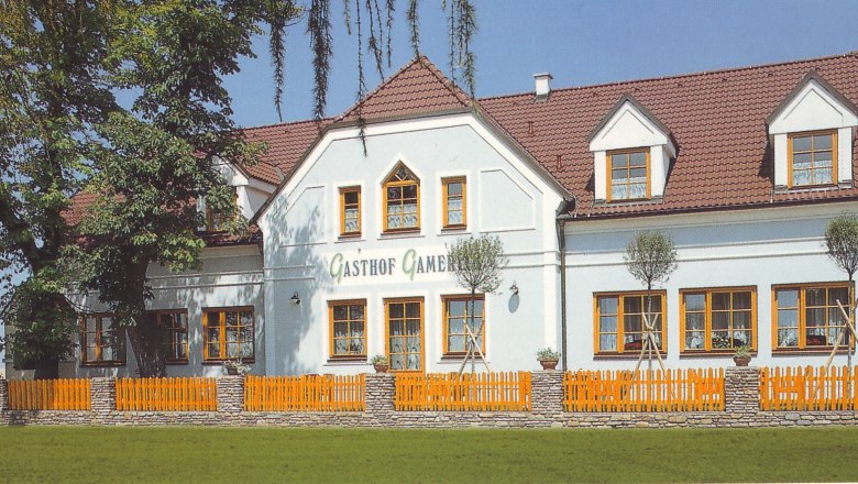 Gasthof Gamerith, © Gasthof Gamerith A traditional inn with a white façade and red roof tiles, surrounded by trees and a wooden fence.