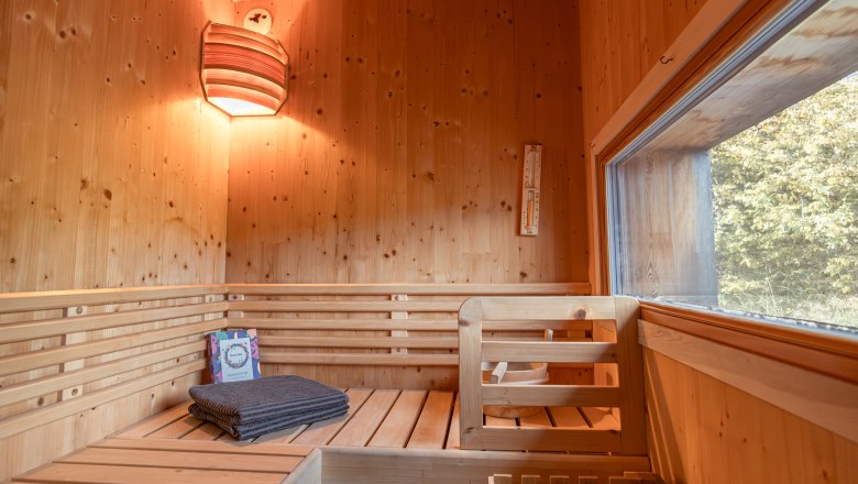 roo'n, © Niederösterreich Werbung / Maximilian Pawlikowsky Interior view of a wooden sauna with benches, towel and window.