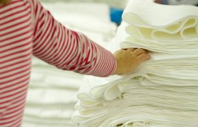 HERKA terry toweling, © HerkaGmbH-IreneKernthaler-Moser A hand touches a pile of white towels.