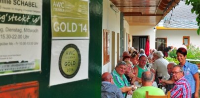 Buschenschank Schabel (typical tavern), © Familie Schabel People sit at a long table in a covered outdoor area of a restaurant.