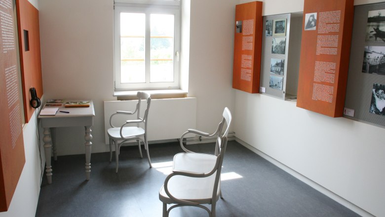 Egon Schiele's birthplace, © Stadtgemeinde Tulln, Andreas Pimperl Interior view of a museum room with white chairs, a table and information boards on the walls.