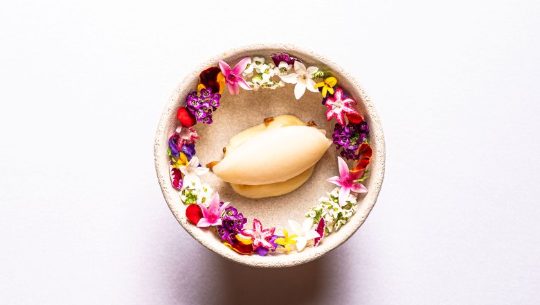 Tarte Tatin, © Claus Kadrnoschka A dessert in a bowl surrounded by colorful edible flowers.