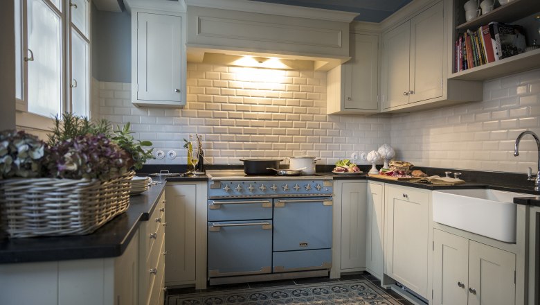 Kitchen of the villa, © Matthias Kronfuss Elegant kitchen with blue oven, white cupboards and tiles.