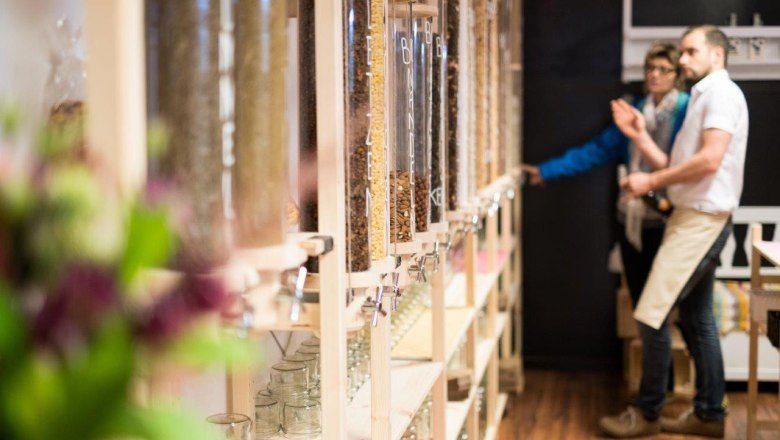 d'Greisslerei in St. Leonhard/Forst, © Jürgen Thoma photography Interior view of an unpackaged food store with dispensers for loose food and two people in the background.