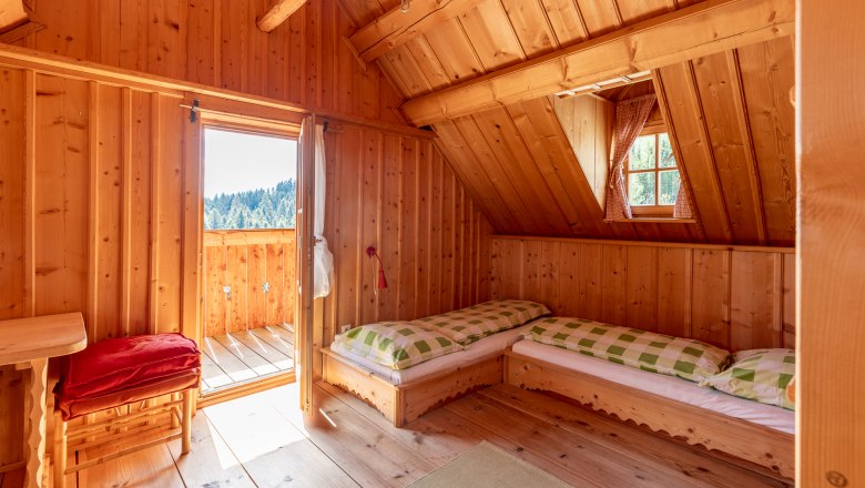 Bedroom, © Wiener Alpen / Christian Kremsl Bedroom with wood paneling, two beds, a window and an open door to the balcony.