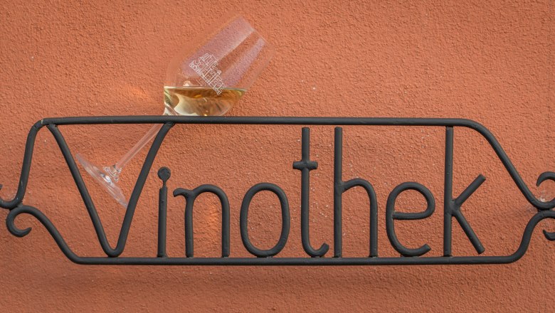 Loving details inside and out, © Alte Schmiede Schönberg Metal sign with the inscription 'Vinothek' and a wine glass on a red wall.