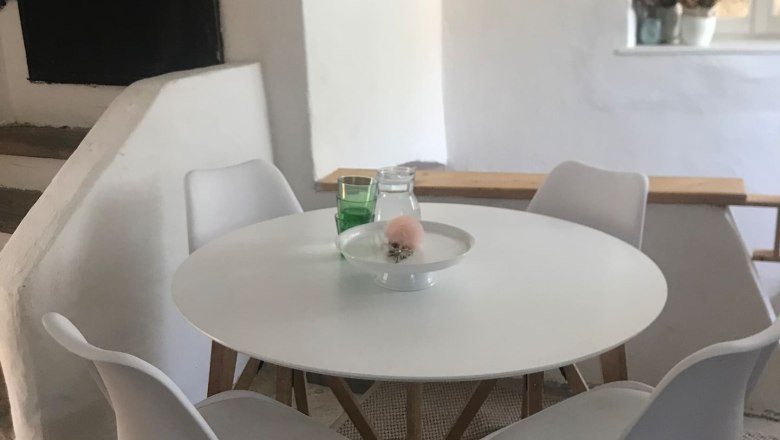 Sitting area, © Familie Stagard Modern seating area with round table and four white chairs in a bright room.