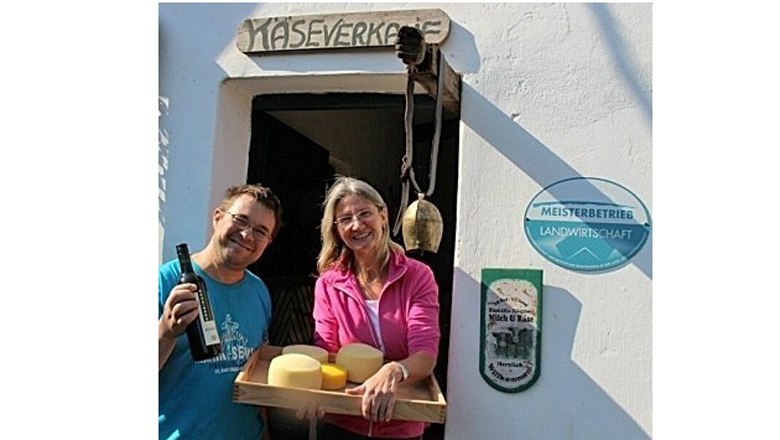 Farm store, © Fam. Rögner Two people in front of a farm store with cheese and wine.