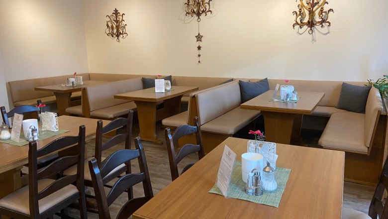 Breakfast area, © Wiener Alpen Cozy breakfast area with wooden tables and upholstered benches, decorated with wall ornaments.