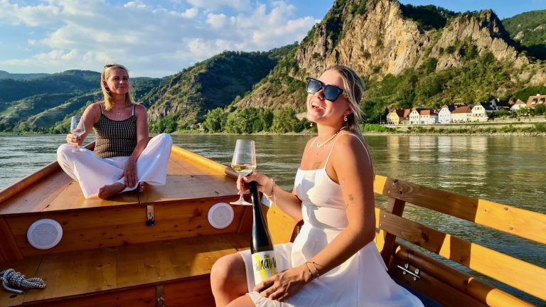 Anchorage Wachau on tour, © Ankerplatz Wachau Two women on a boat in the Wachau, enjoying wine with a view of the mountains.
