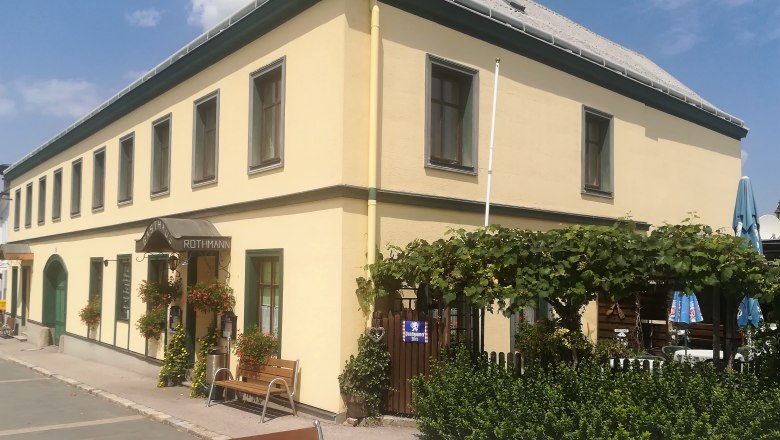 Gasthaus zur Gemütlichkeit Hochwolkersdorf, © Wiener Alpen Yellow restaurant with green window frames, garden and plants in front of the entrance.