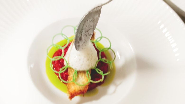 Feel-good guarantee, © Nicolas Engel An artfully presented dish on a white plate, decorated with foam and green garnishes.