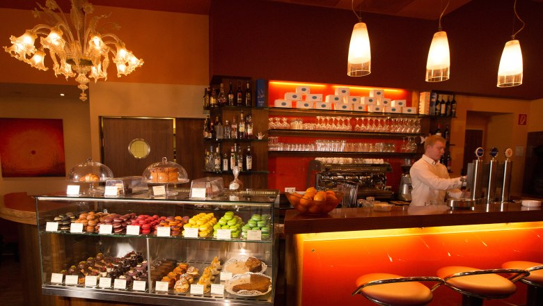 Cafe Helmut & Helmut, © schwarz-koenig.at Interior view of a café with counter, bar stools and pastry display case.
