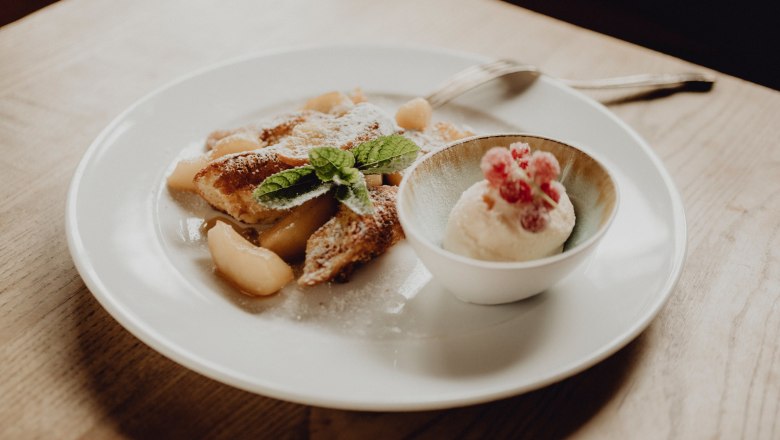 The name says it all: apple pancakes with curd rum ice cream, © Niederösterreich Werbung/Rita Newman A plate of apple pancakes and a bowl of curd rum ice cream, garnished with mint leaves and red berries.