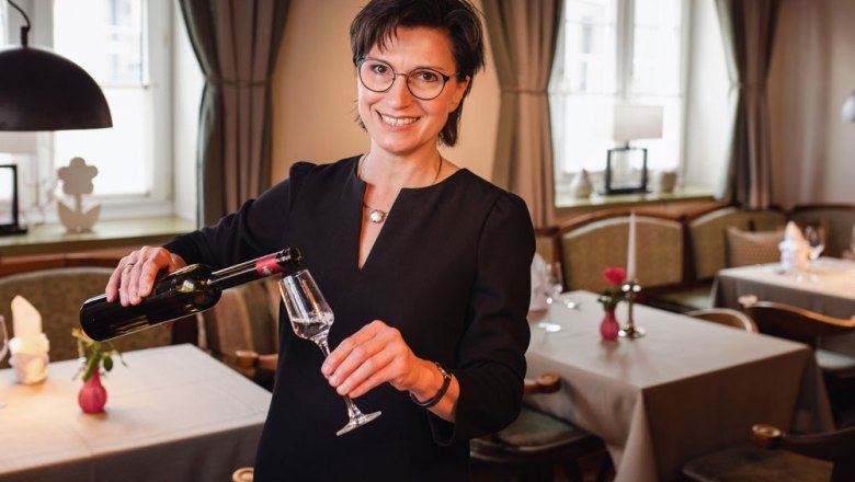 Perfect service and hospitality, © Niederösterreich Werbung/Daniela Führer A woman in a restaurant pours wine into a glass.