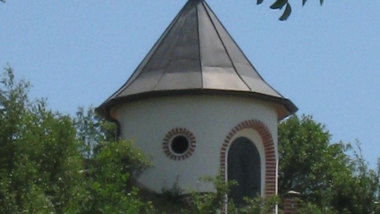 Kammersdorf water tower, © Marktgemeinde Nappersdorf-Kammersdorf A round water tower with a pointed roof and weather vane, surrounded by trees and meadows.