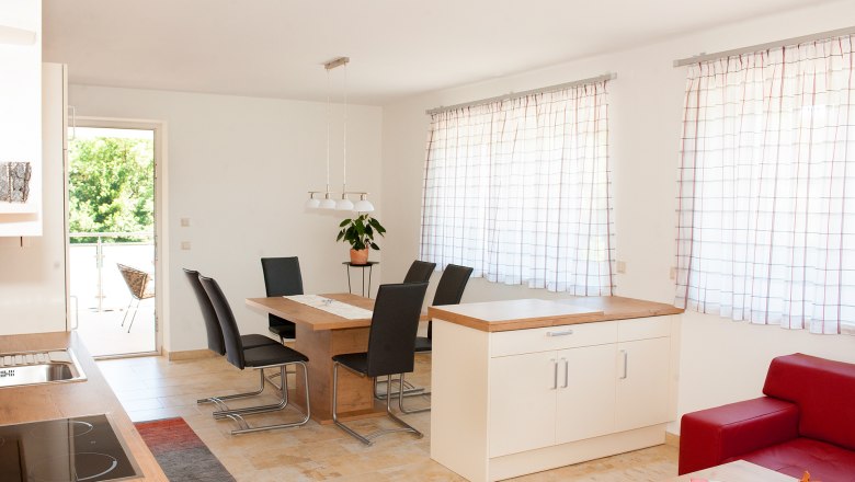 Dining area, © Familie Harrauer Modern dining area with wooden table, black chairs and large windows with curtains.