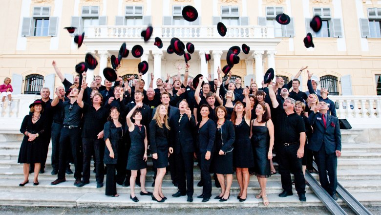 Rubin Carnuntum Wineries, © Tom Lamm Group of people throwing hats in the air in front of a historic building.
