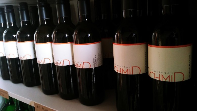 Biohof Schmid, © Schmid Wine bottles with the label 'Biohof Schmid' on a shelf.