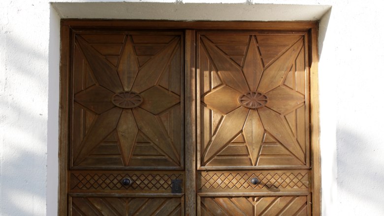 Cellar door, © Weinviertel Tourismus / Wurnig Wooden door with geometric patterns in a white wall.