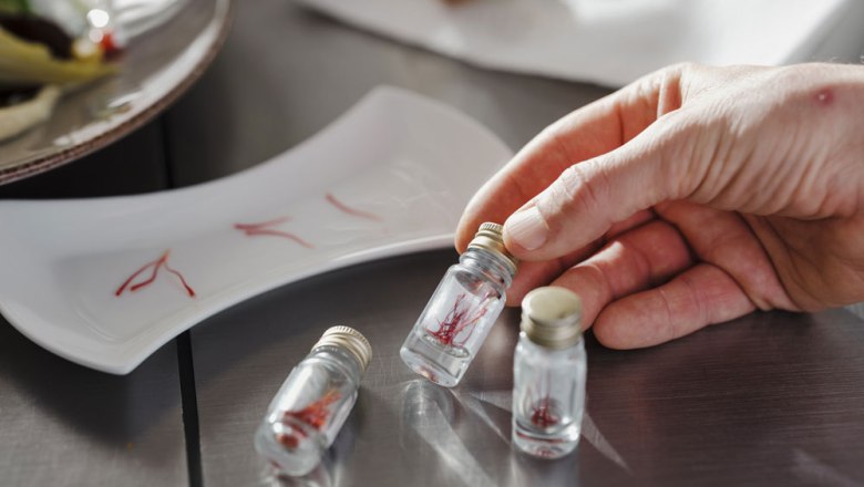 Saffron from our own cultivation, © Niederösterreich Werbung/Michael Reidinger Her hand holds a small glass vial with saffron threads, next to it two other vials and a plate with saffron.