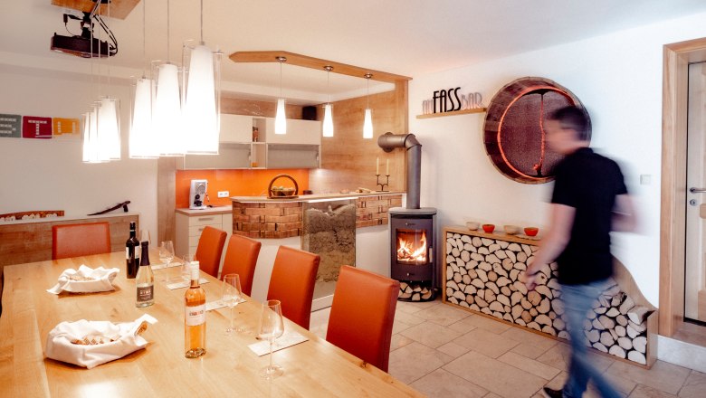 Tasting room, © Astrid Bartl A tasting room with wooden table, wine glasses, fireplace and modern lighting.