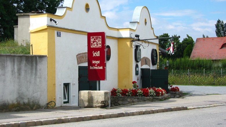 Seidl-Keller, © Fam. Seidl Seidl winery with yellow building and red sign.