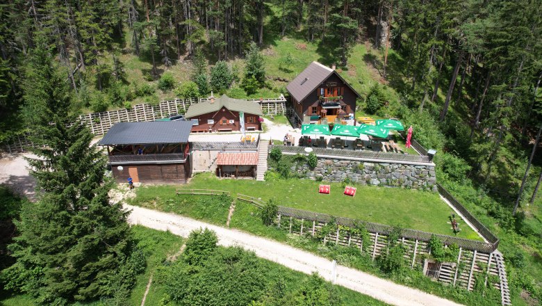 Potschacherhuette, © Georg Eder Aerial view of the Potschacherhütte in a wooded area with surrounding trees and a terrace with sunshades.