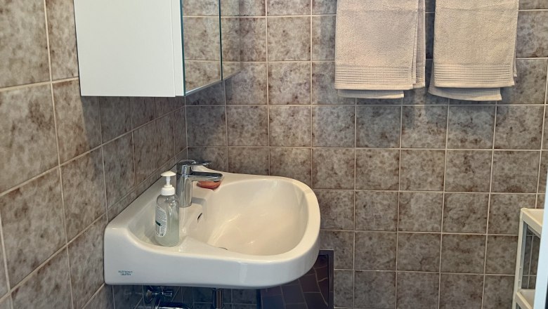 Bathroom, © Waltraud Forstner A bathroom with washbasin, mirror, towels and tiles.