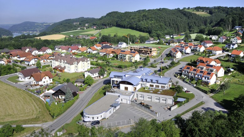 Community center, © Gemeinde Aerial view of a village with community center and surrounding houses in a green hilly landscape.