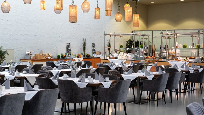 Eventhotel Pyramide, Restaurant Hemingway, © Eventhotel Pyramide GmbH Interior view of a stylish restaurant with laid tables and hanging lamps.