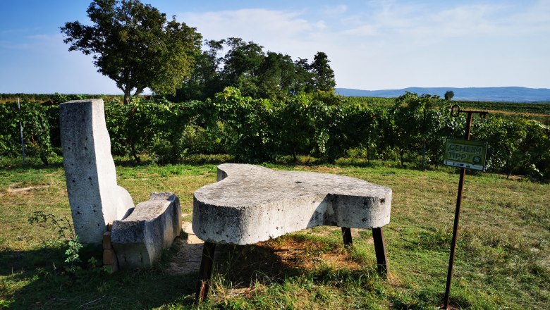 Relax and enjoy the landscape, © Weinstraße Weinviertel Stone bench and table in a vineyard with an 'insider tip' sign.
