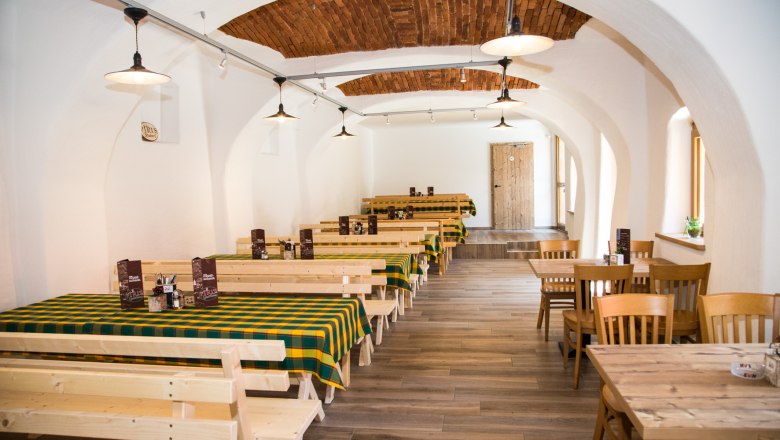 Parlor, © Christian Piribauer Traditional interior of an inn with wooden tables and checkered tablecloths.