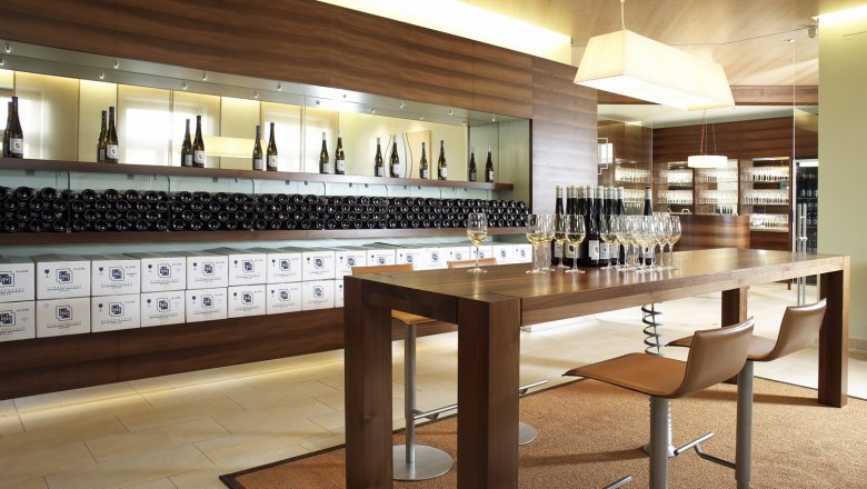 Tasting room, © Weingut Wannemacher Modern tasting room with wooden table, wine glasses and wine bottles.