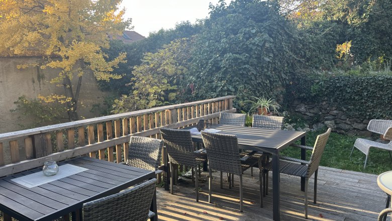 Pension Altes Rathaus in Dürnstein, © Familie Fürtler Terrace with wooden tables and chairs, surrounded by autumnal trees and plants.