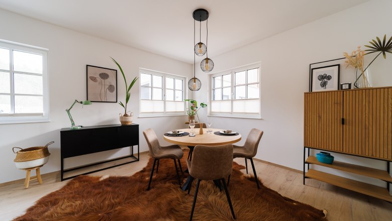 Apartment Wackelstein, © Göllitzhof Modern dining room with round table, four chairs, fur rug and minimalist decoration.